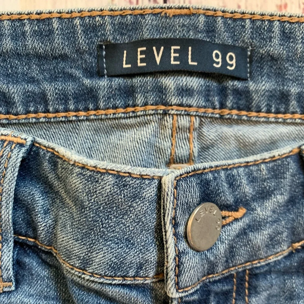 Level 99 jeans. Gold/silver design on bottom. Mid rise. Size 27.